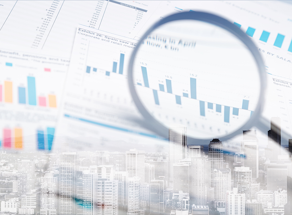 Fotomontage: ett förstoringsglas, börskurser och diagram samt skyskrapor i ett finanscentrum