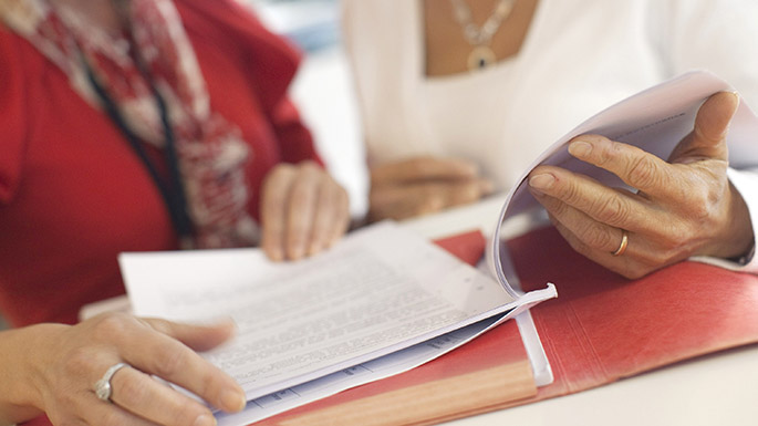 Photo: close up picture of people turning over pages in a folder